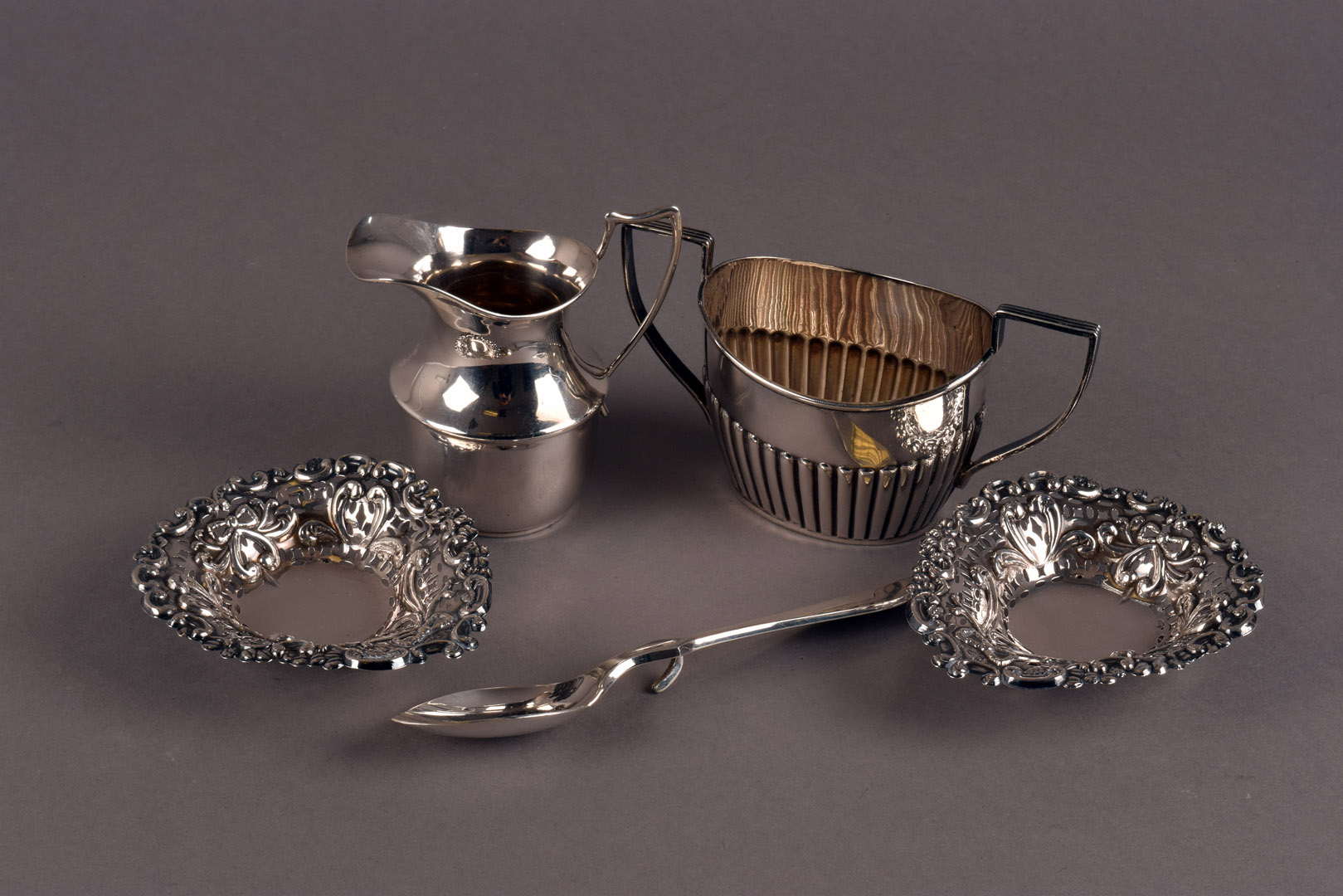 A pair of late Victorian silver pierced dishes, together with a George V silver cream jug, a