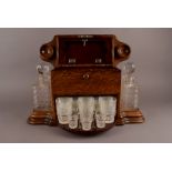 A Victorian or Edwardian oak drinking compendium, the shaped box with hinged lid opening to reveal