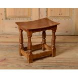 ENGLISH OAK FOOT STOOL, DESIGNED BY ROBERT MOUSEMAN THOMPSON With an incurved seat, raised on turned