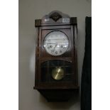 A mahogany cased wall clock with visible pendulum.