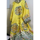 A Chinese yellow silk type robe embroidered in gold thread with flying dragons and bats