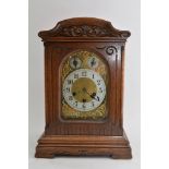 An oak cased mantel clock, the silvered dial with