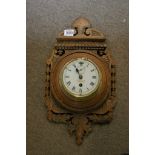 A Brass Wall clock mounted on to a carved oak shield Hutton of London