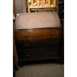 An oak bureau fitted with three drawers.