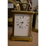 A brass case carriage clock, the enamel dial with