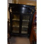 An ebonised Art Nouveau display cabinet with scrol