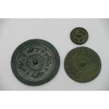 Three small, Chinese bronze mirrors, one face being polished, the other with various patterns