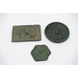 Three small Chinese bronze mirrors with polished faces: one discoid, one rectangular and one a