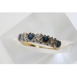 A gold ring set with a row of sapphires and diamonds