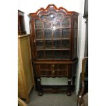 A single glazed door display cabinet enclosing three shelves above two drawers.