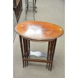 A nest of three oval shaped mahogany tables with quarter veneer tops.