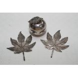 A white metal apple and pair of silver maple leaves