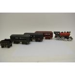 A cast iron model of a train tender and three carriages