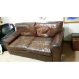 Chestnut brown 2 seat leather sofa on bun feet. Measures approx: 174cm wide, 94cm deep, 77cm high