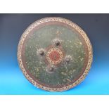 A tooled and painted circular shield with four metal studs