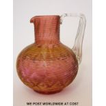 An unusual cranberry glass jug possibly by James Powell with applied ribbed decoration and further