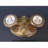A set of brass postage scales with ceramic plaques of cherubs to the pans and stack of weights to