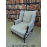 An upholstered wingback armchair with carved oak frame