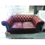 A red leather two seat Chesterfield sofa