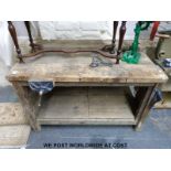 A rustic wood working bench with vice and clamp