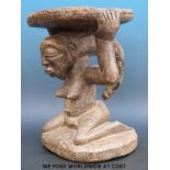 An African tribal stool with a kneeling female figure supporting the seat on her head (33cm tall)