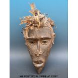 An African tribal mask with feathers and nails to the top,