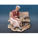 A Capodimonte figure of a lady sitting on a bench with two dogs