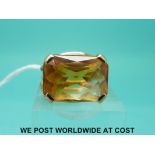 A yellow metal ring set with a cushion cut citrine,