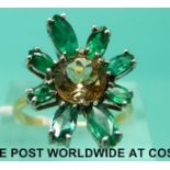 An 18ct gold ring set with emeralds and a topaz in a large floral design (size O)