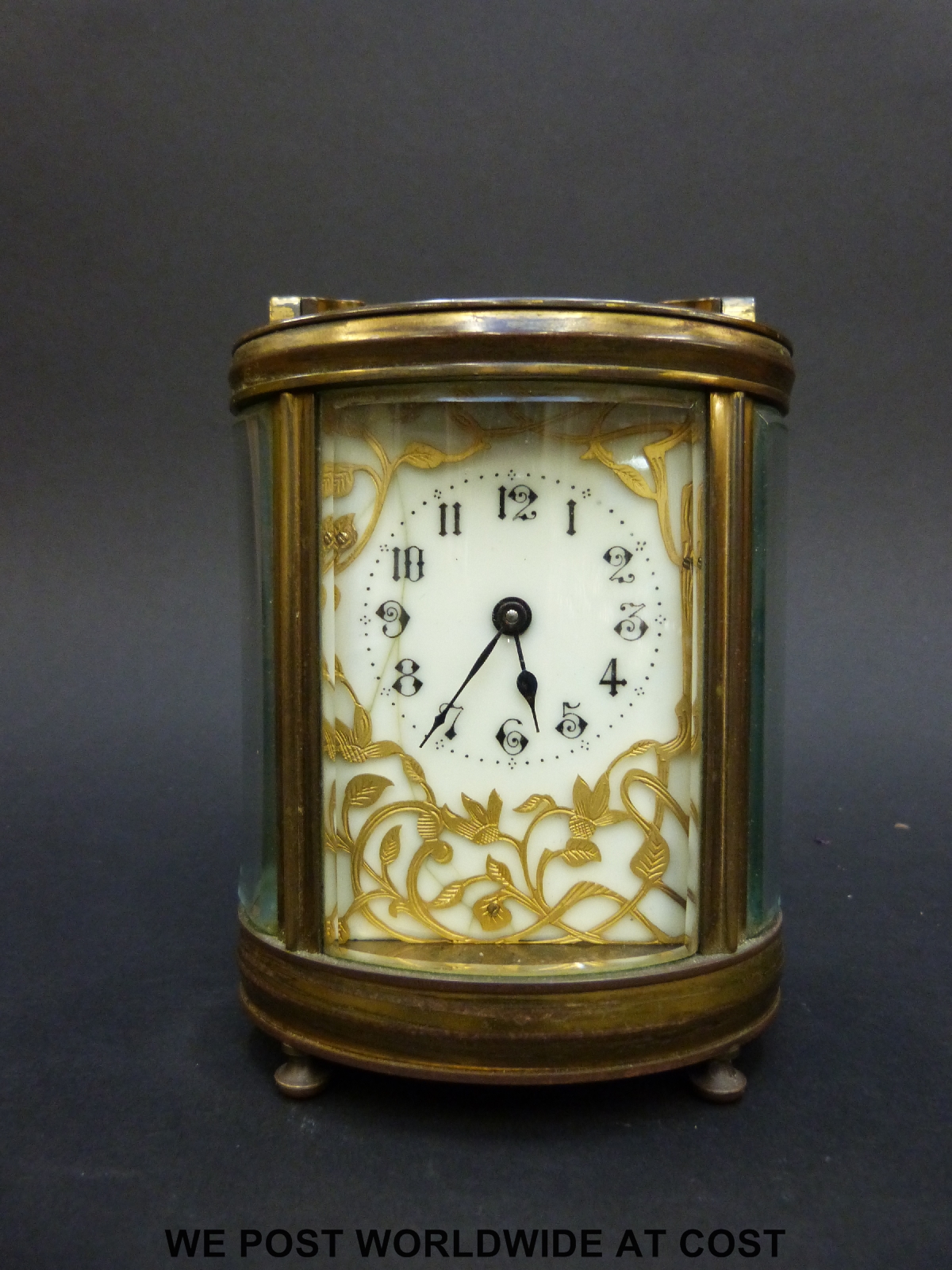 A mantel clock of oval section with bevelled glass and pierced gilt foliate panel to dial