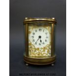 A mantel clock of oval section with bevelled glass and pierced gilt foliate panel to dial