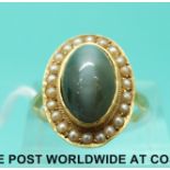 An 18ct gold ring set with a star sapphire surrounded by seed pearls (size L)