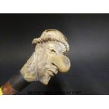 A carved deer horn walking cane with a caricature knop,