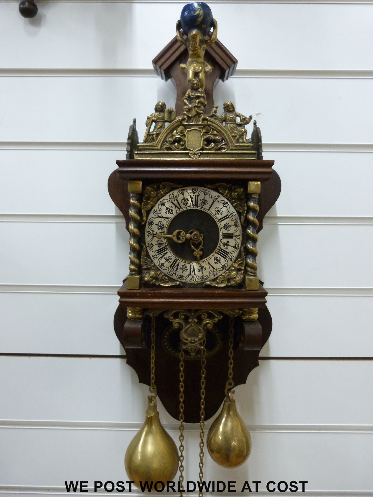 A continental wall clock with brass figural decoration and two large brass weights,