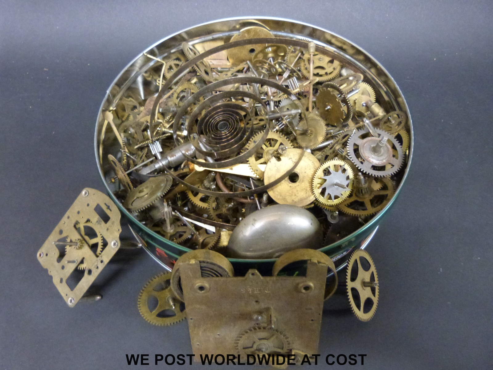 A tin of spare clock movement parts,