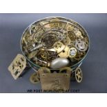 A tin of spare clock movement parts,