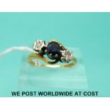 An 18ct gold ring set with a round cut sapphire flanked by two diamonds in a twist setting (size M)