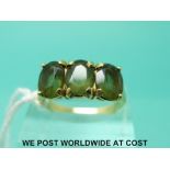 A yellow metal ring marked 14k set with three green garnets (size O)