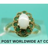 A 9ct gold ring set with an opal surrounded by emeralds (size K)