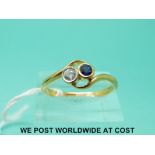 A 22ct gold ring set with a diamond and a sapphire in a twist setting (size U)