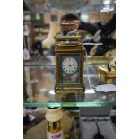 An antique engraved brass and porcelain miniature carriage timepiece, height including handle 9.5cm.