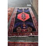 A geometric black ground rug, having red central medallion, 281 x 148cm.