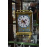 A brass and porcelain carriage timepiece, height including handle 14cm.