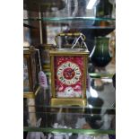 A brass and porcelain carriage clock, with alarm, height including handle 14.5cm.