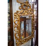 A carved giltwood framed wall mirror, 100cm high x 65cm wide.