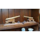 A pair of oak and brass desk cannon ornaments, 20cm wide.