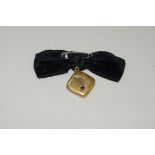 A 14ct (not 15ct) gold gem set square locket, on black velvet bow.