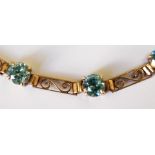 A 9ct gold and blue zircon scroll bracelet.