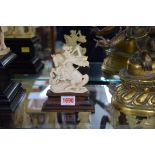 An antique carved ivory figure group of St George and the Dragon, 10cm high, on wooden socle.