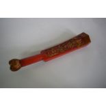 A Chinese red lacquered and parcel gilt carved wood wrist wrest or scroll weight, 33cm long.